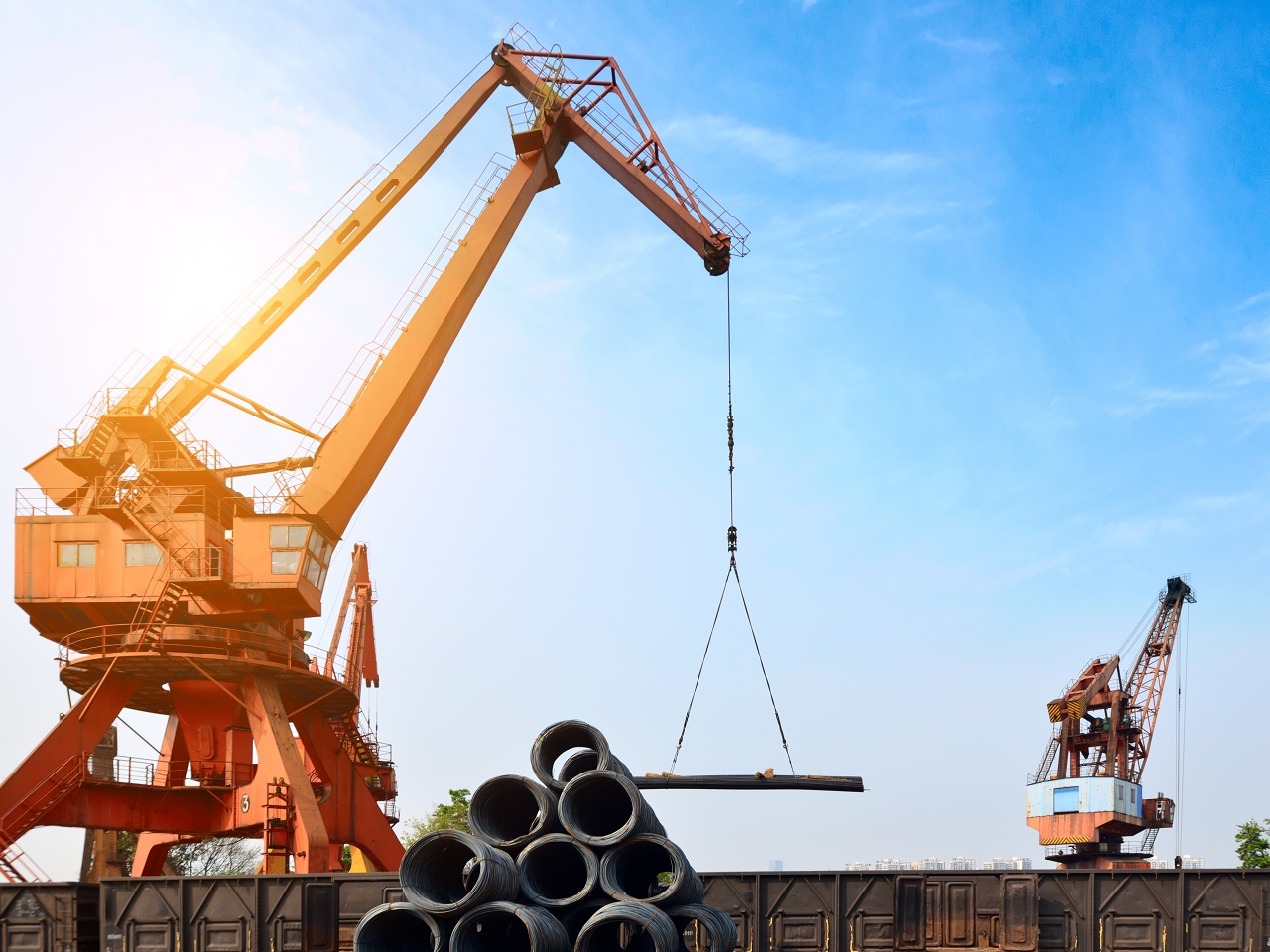 Guindastes fazendo manobra com carga de aço no porto