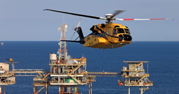 Helicóptero amarelo decolando de plataforma offshore