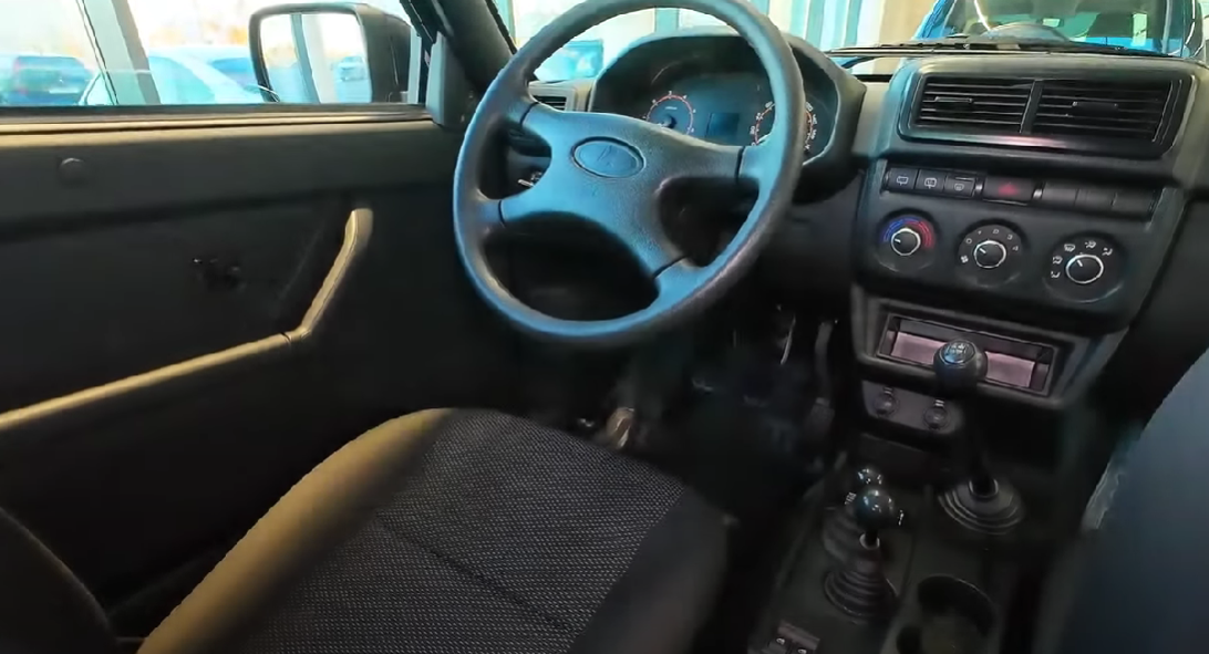 El Lada Niva tiene dos cambios porque utiliza una caja de transferencia adicional, además del cambio principal. Esto es típico de vehículos off-road, permitiendo que el conductor alterna entre modos de tracción para diferentes terrenos. El cambio principal ofrece las marchas tradicionales, mientras que la caja de transferencia permite seleccionar entre tracción 4×2 y 4×4, además de ofrecer marchas reducidas para situaciones que exigen más fuerza, como subir terrenos empinados, atravesar barro o nieve. Esta configuración aumenta la versatilidad y la capacidad off-road del jeep, haciéndolo ideal para terrenos desafiantes.