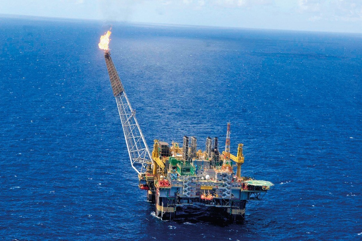 Plataforma de petróleo em alto-mar com queima de gás visível no flare