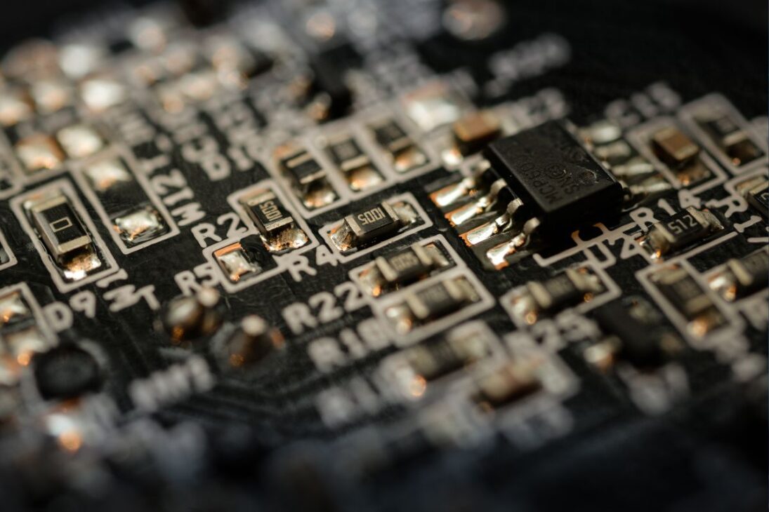 Cierre de placa electrónica con microchip y componentes SMD soldados, ilustrando la miniaturización y precisión de la tecnología digital moderna.