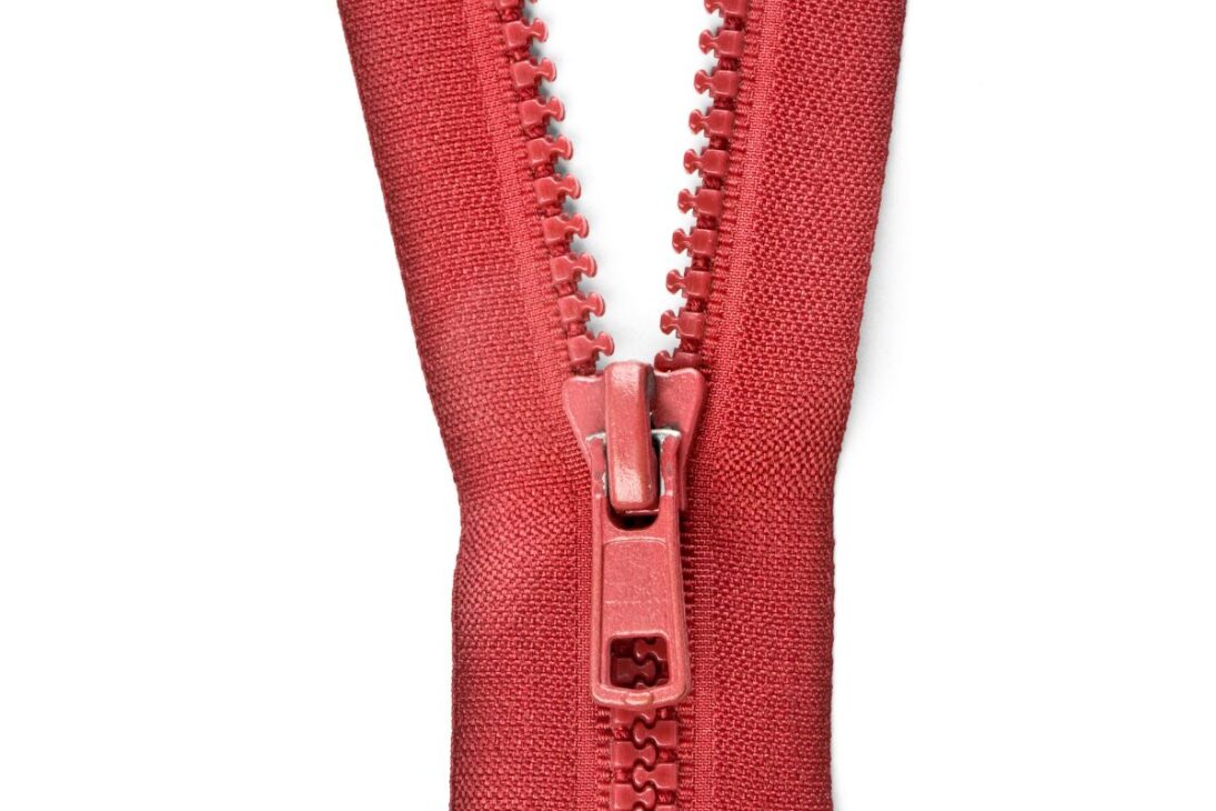 Zíper de plástico rojo con dientes grandes y visibles, con el tirador en la parte inferior central, sobre un fondo blanco puro.