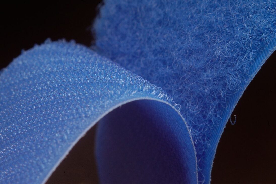 Vista ampliada de un fecho de velcro azul, mostrando la estructura detallada de los lados del gancho y del lazo.
