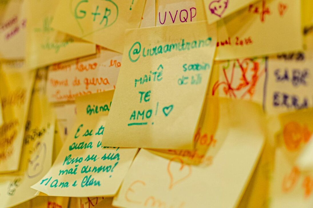 Pared cubierta por una colección densa de post-its coloridos y amarillentos con mensajes escritos a mano.