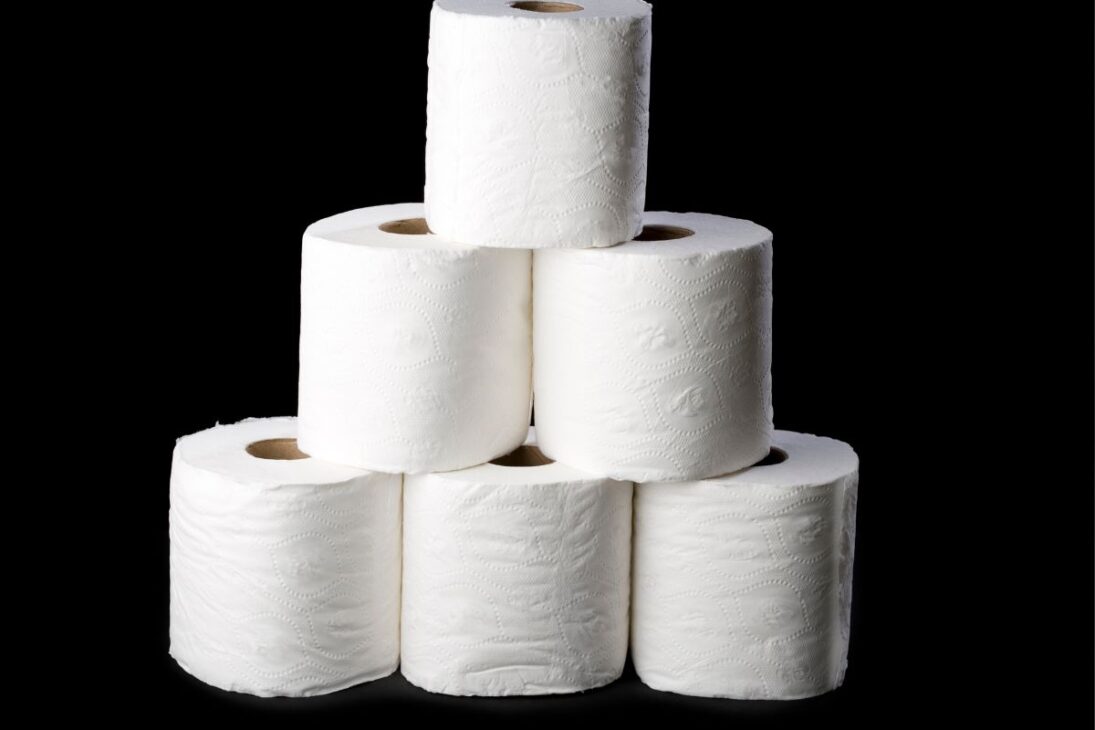 Pila de rollos de papel higiénico blanco sobre un fondo negro sólido.