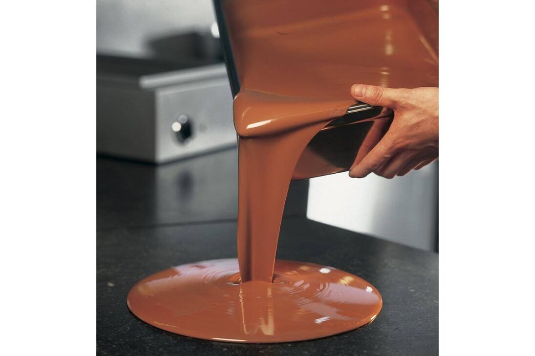 Esta es la etapa más crítica y científica de todo el proceso. La manteca de cacao, la grasa natural del cacao, puede solidificarse en seis formas diferentes de cristales. Solo una de ellas, la estable "Beta V", resulta en un chocolate que es brillante, firme, que quiebra con un estallido seco característico (el "snap") y que no se derrite fácilmente al tacto.