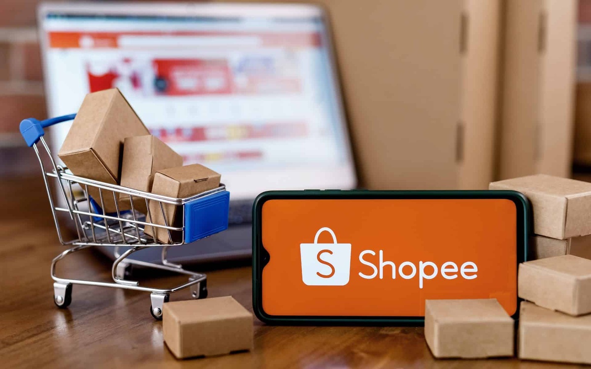 Aplicativo Shopee exibido em smartphone com mini carrinho de compras e caixas
