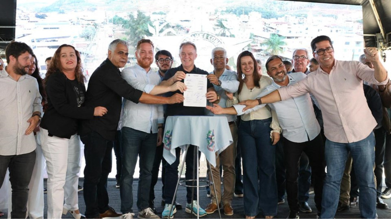 Imagem de um gigantesco edifício residencial em formato curvo, iluminado pelo pôr do sol, com caracteres chineses vermelhos em destaque à direita. O prédio possui dezenas de andares e centenas de janelas, sugerindo alta densidade populacional.