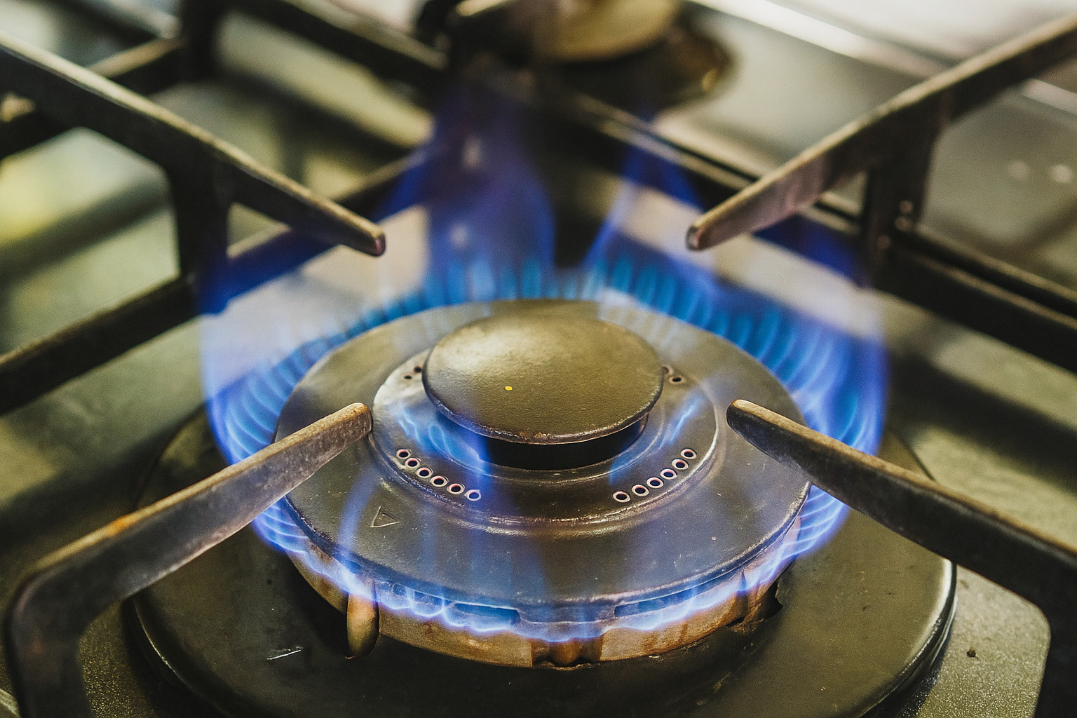 Fogão com chama azul acesa em um queimador moderno.