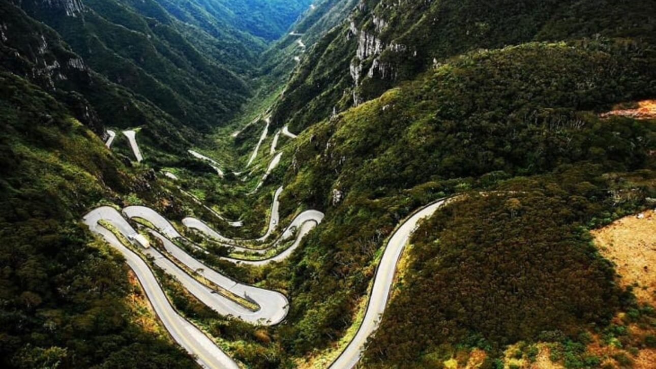 Vista aérea da SC‑390 na Serra do Rio do Rastro, com curvas sinuosas entre cânions e Mata Atlântica preservada. (Imagem: Viajali)