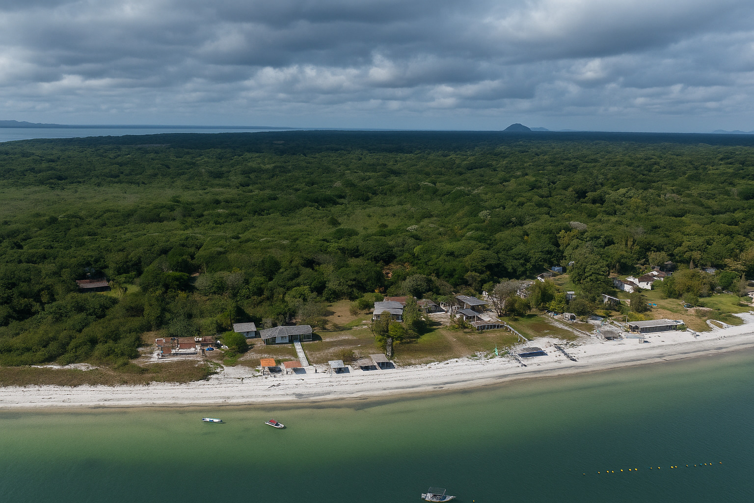 Vista aérea da costa com mar azul e ondas suaves sob céu ensolarado.