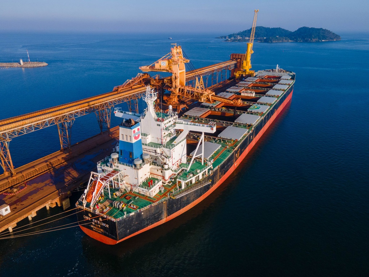 Navio cargueiro atracado em terminal portuário com carregamento de minério
