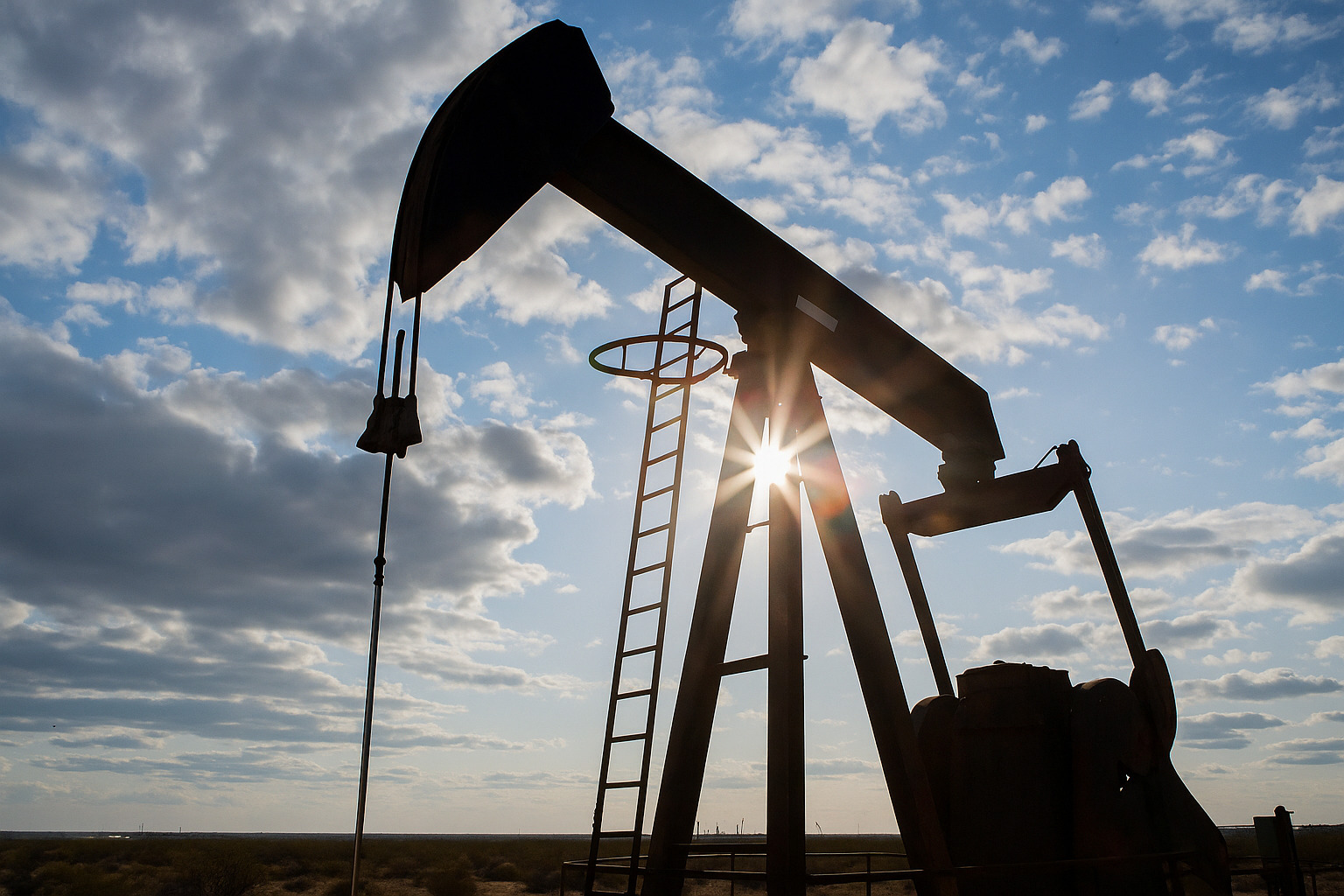 Bomba de extração de petróleo em operação com céu parcialmente nublado ao fundo.