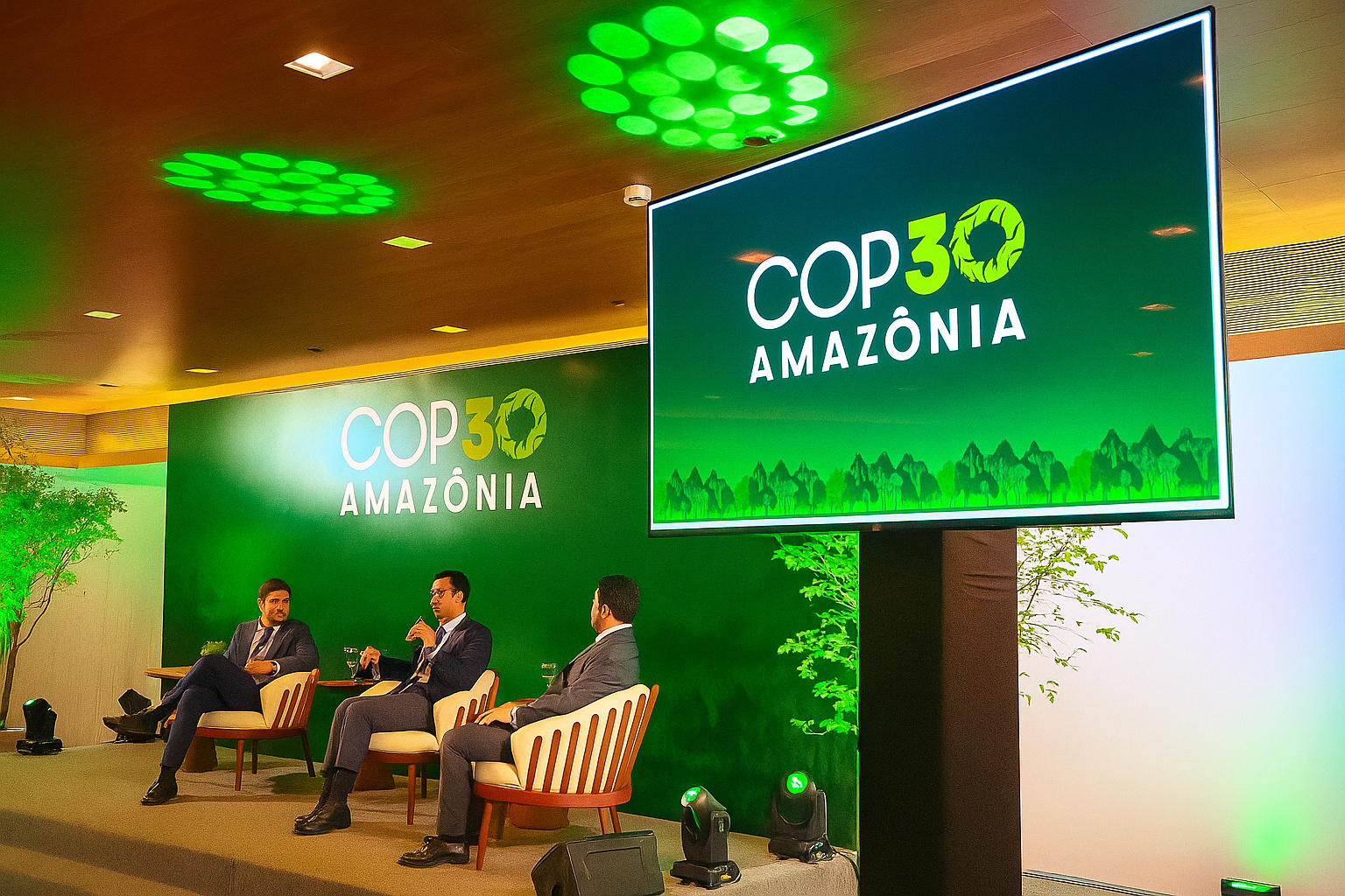 Painel de debate durante a COP30 Amazônia com três homens em um palco iluminado por luzes verdes.