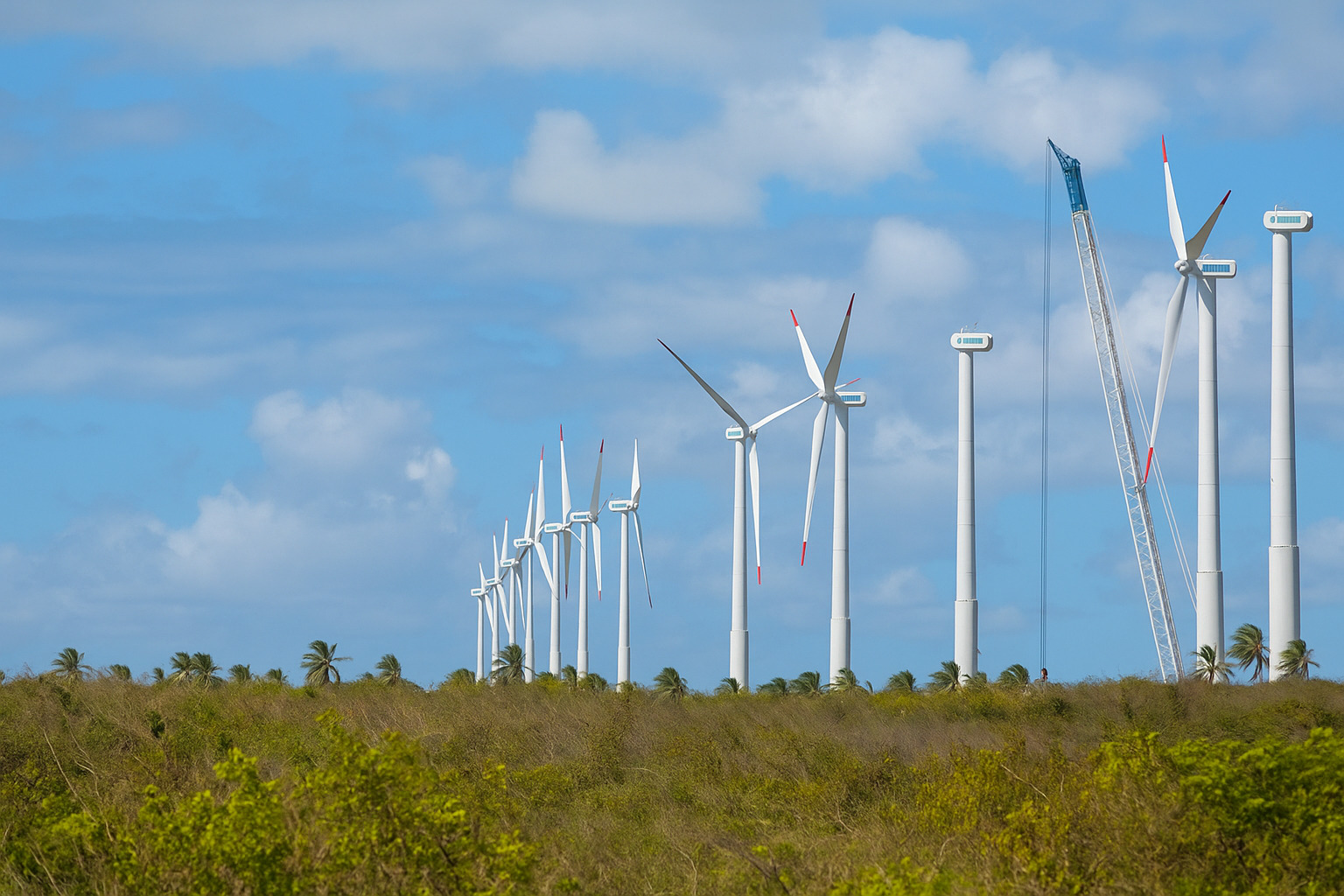 Parque eólico com turbinas gerando energia sob céu parcialmente nublado.