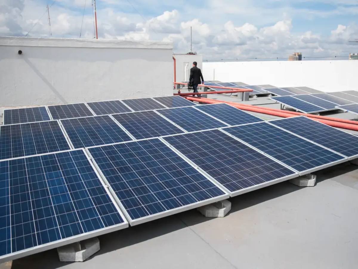 Painéis solares instalados no telhado de um prédio, captando energia solar em um dia parcialmente nublado.