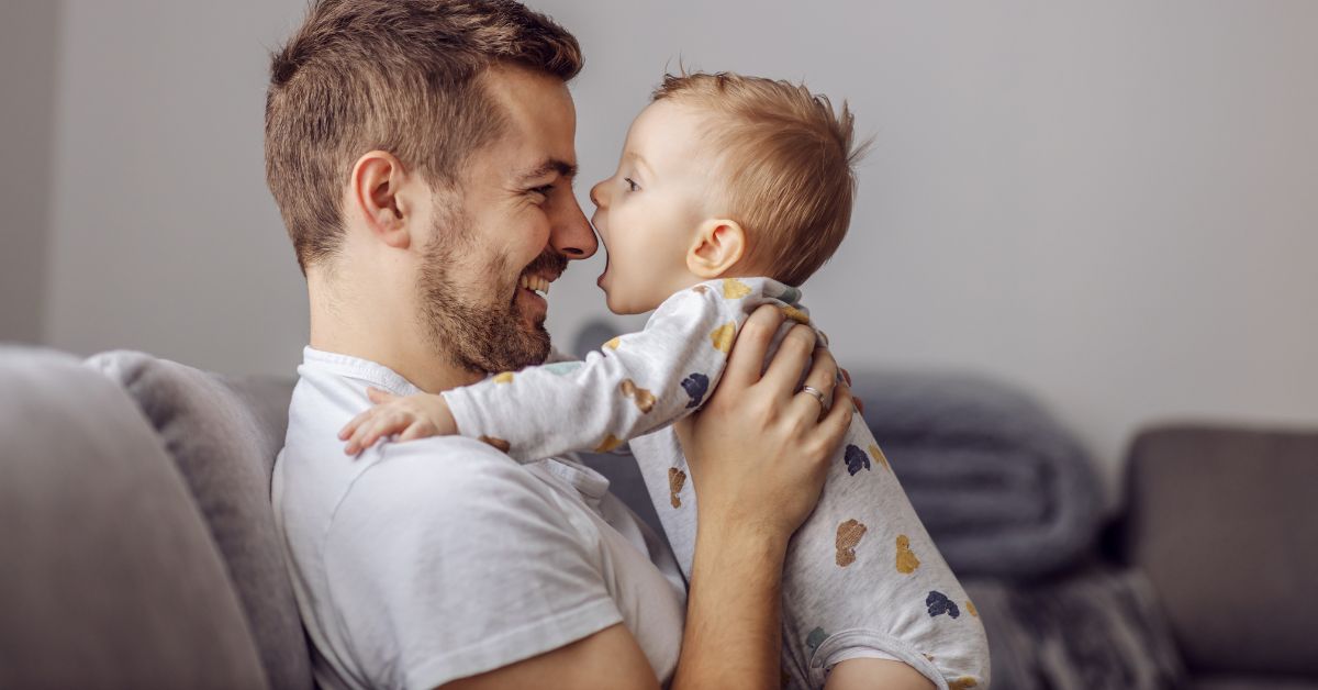 Pai sorridente brinca com seu bebê em casa, simbolizando a nova licença-paternidade de 20 dias aprovada pela Câmara dos Deputados no Brasil.