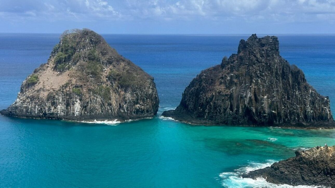 Vista aérea del Morro Dois Irmãos en Fernando de Noronha, con aguas extremadamente transparentes y litoral protegido por la preservación ambiental.” (Imagen: Guia Viagens Brasil)