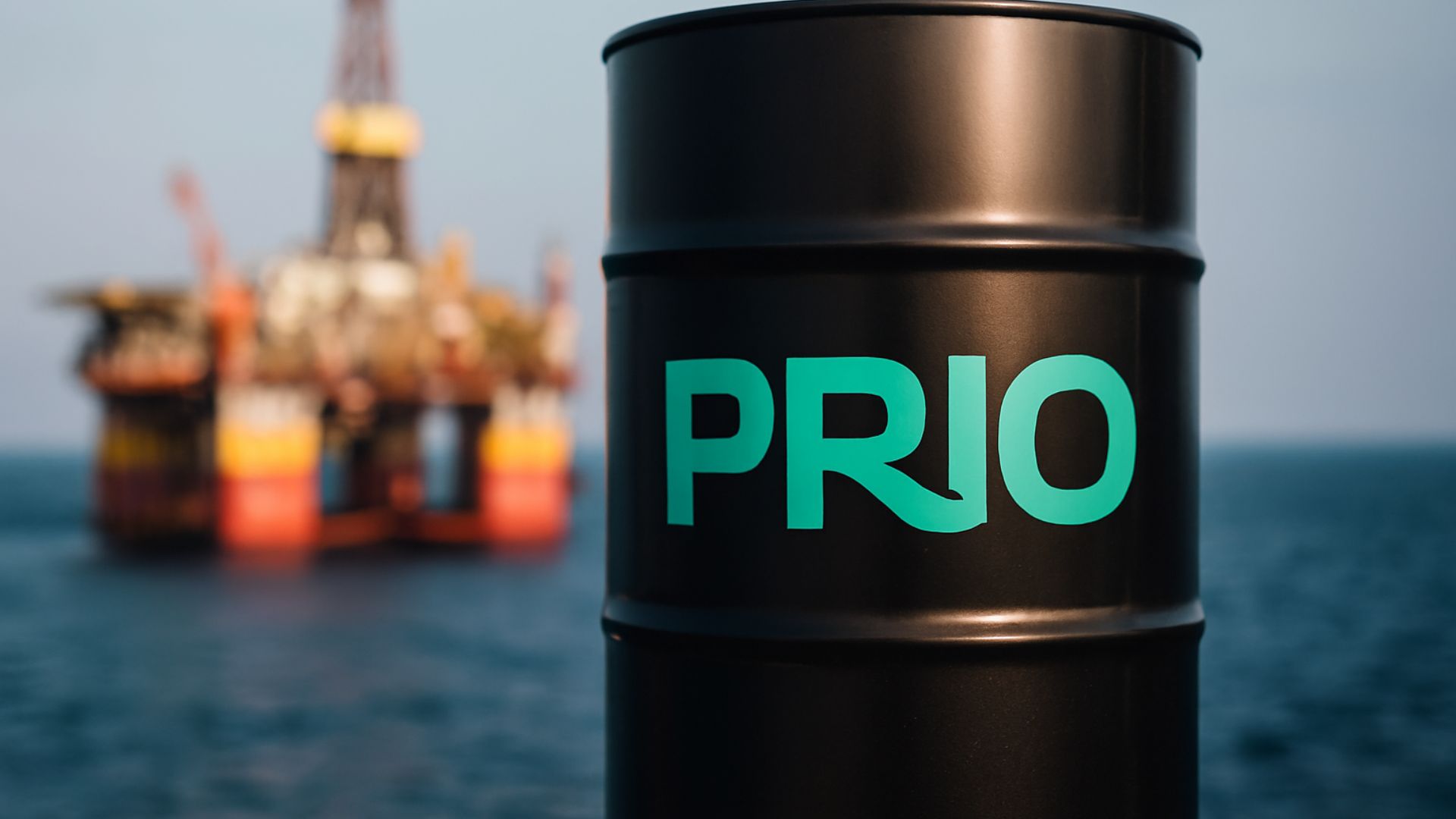 Barril de petróleo com logotipo da Prio em destaque, em primeiro plano, com plataforma offshore desfocada ao fundo sobre o oceano.