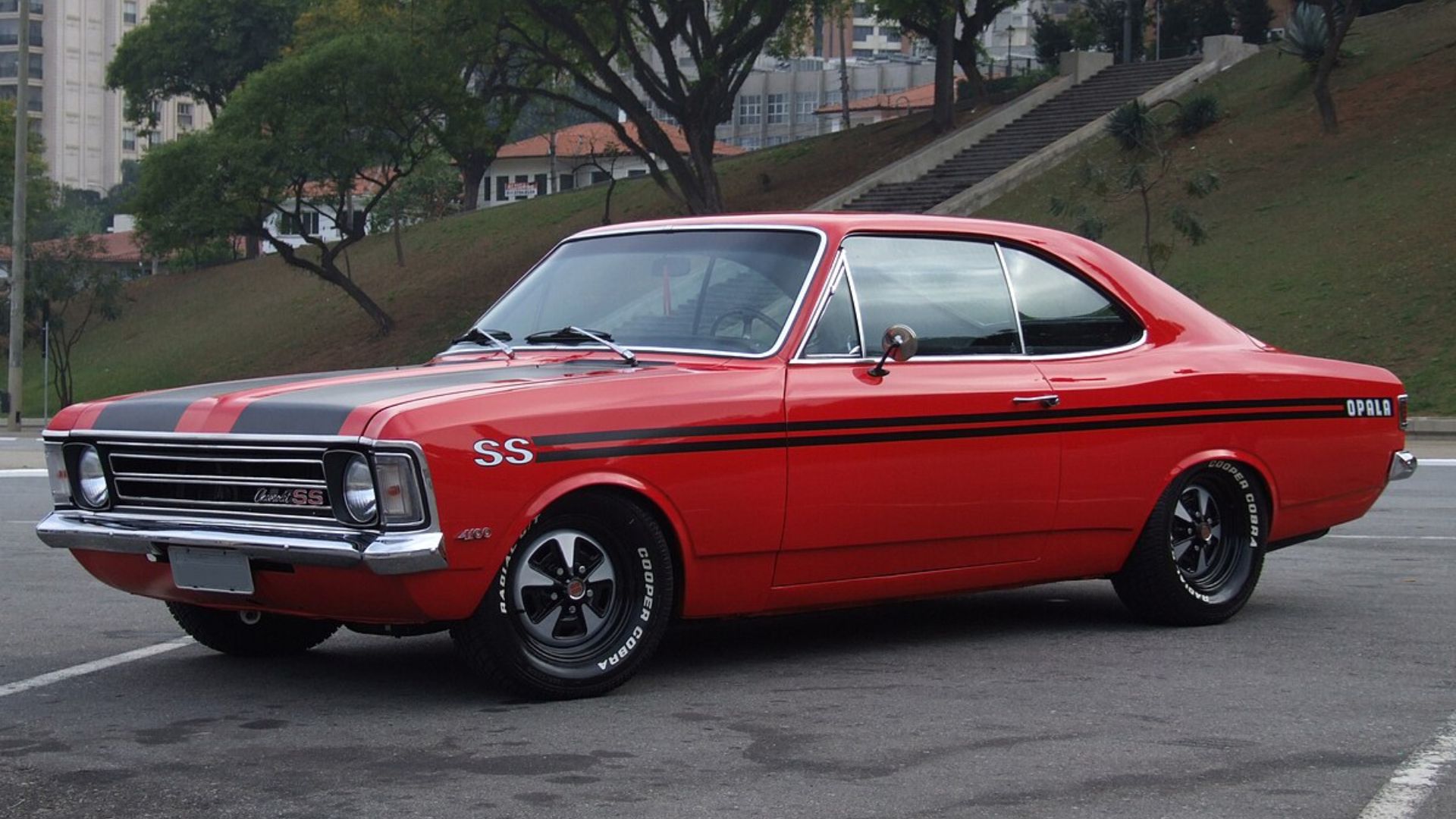 Sedãs clássicos como Vectra, Tempra, Santana, Passat e Opala lado a lado em pátio ensolarado.