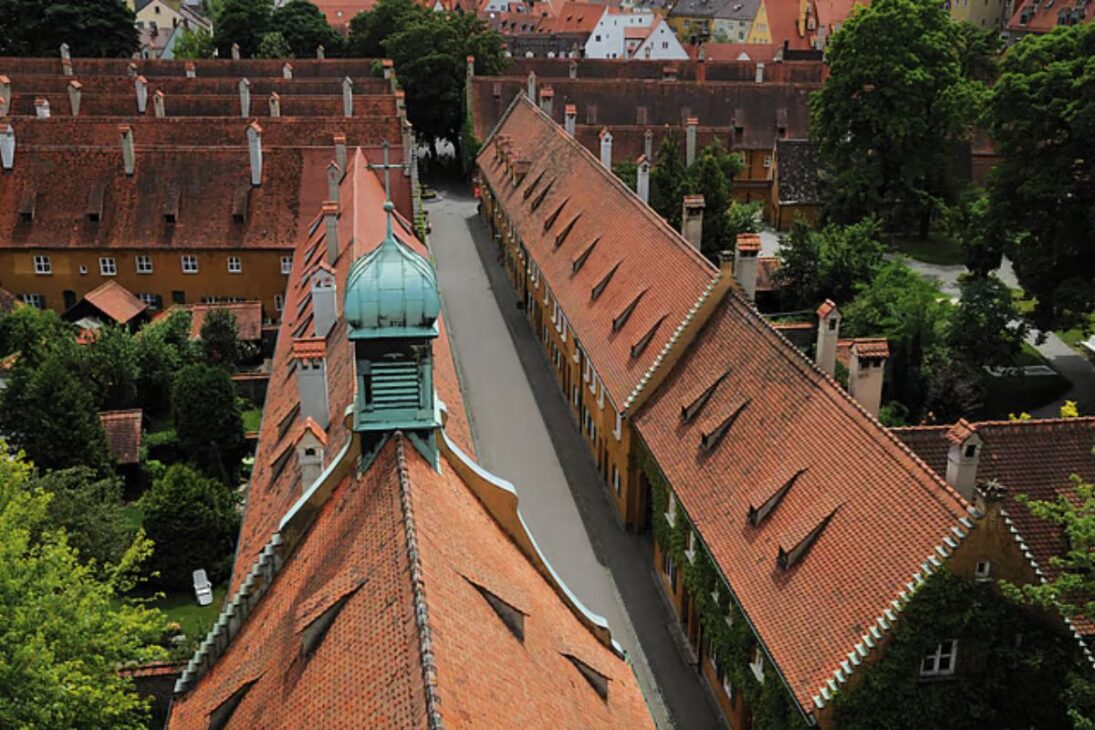 barrio medieval alemán Fuggerei ofrece alquiler simbólico a residentes católicos en villa-museo turística rodeada de reglas históricas, oración diaria y puertas cerradas a las 22h.