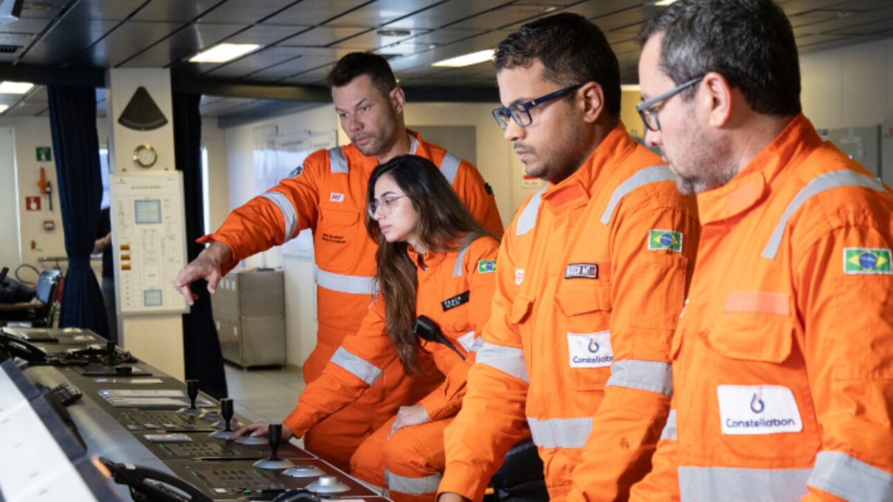 Equipo offshore de la Constellation en sala de control de unidad de perforación, utilizando overoles de seguridad y operando sistemas técnicos en entorno marítimo
