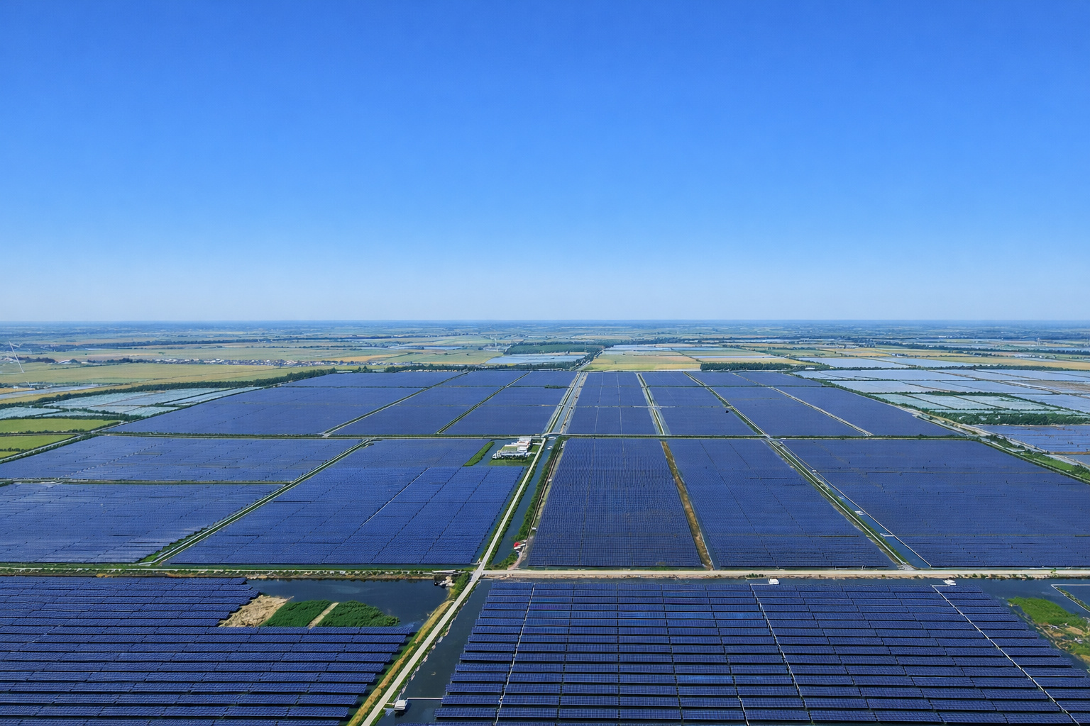 Vista aérea de uma grande usina solar com fileiras de painéis fotovoltaicos sob céu limpo ao meio-dia.