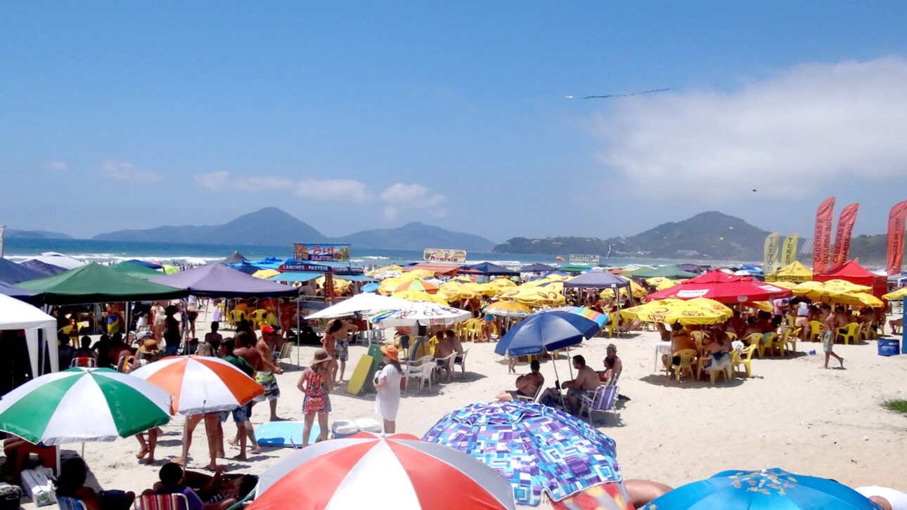 Cobrança antecipada, consumação mínima e praias loteadas por barracas desafiam turistas no litoral de SP durante a alta temporada.