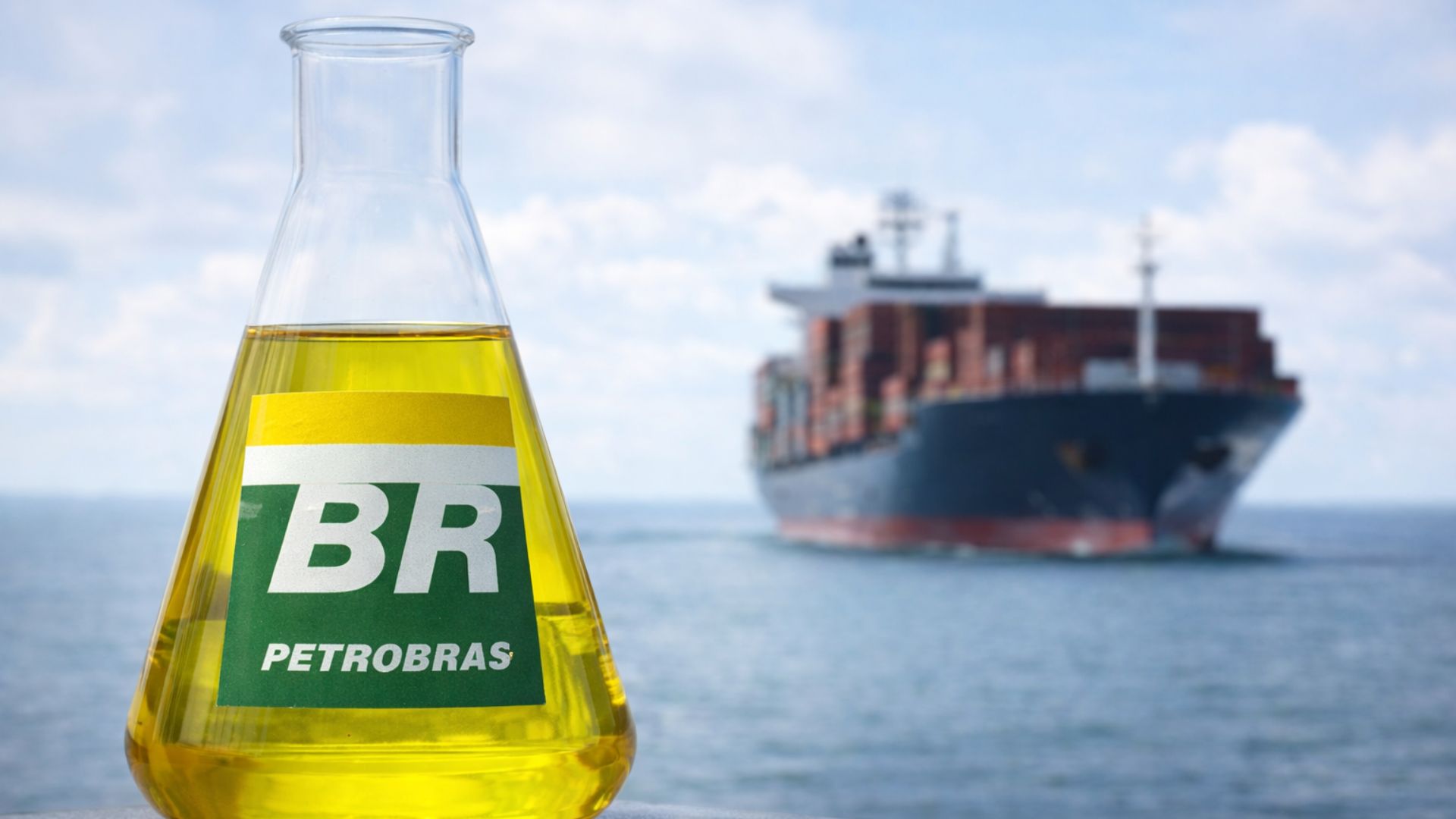 Frasco Erlenmeyer com diesel marítimo sustentável identificado com logotipo da Petrobras em primeiro plano, com navio cargueiro desfocado ao fundo no oceano.