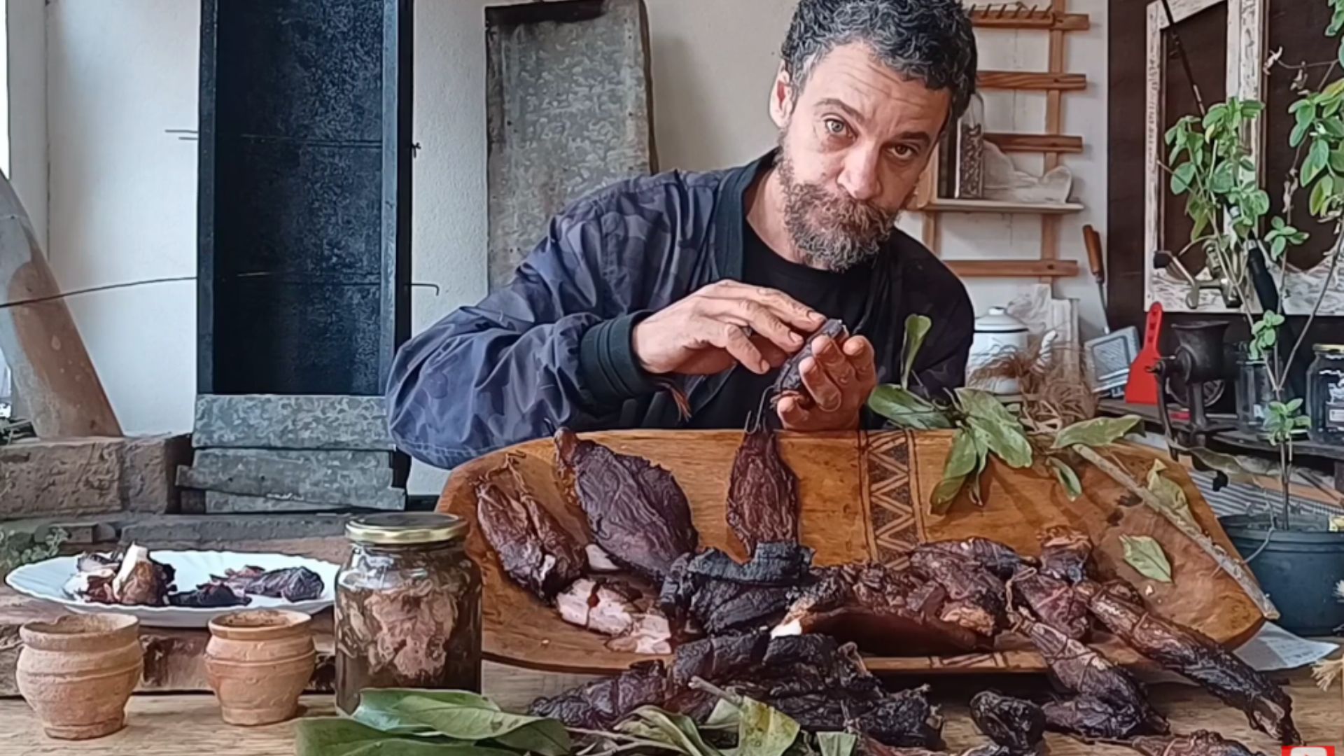 Pescador mostrando peixe e carne defumados após processo de cura para conservação sem geladeira.