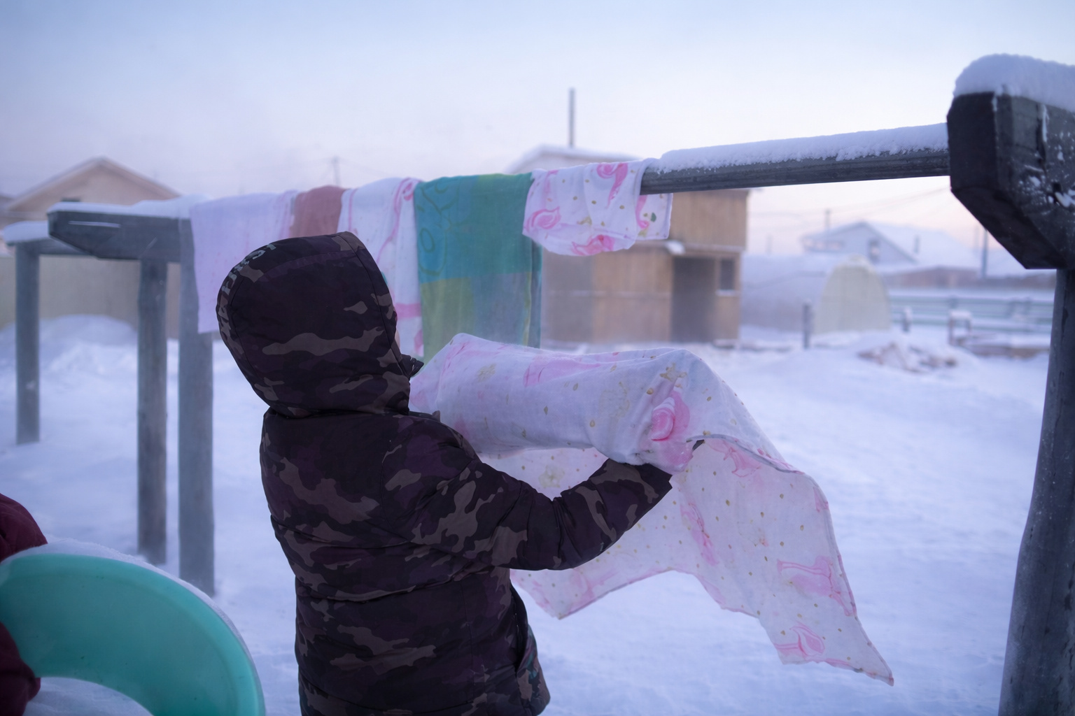 Pessoa pendura roupas recém-lavadas ao ar livre na Yakutia, onde o frio extremo congela os tecidos durante o inverno siberiano.