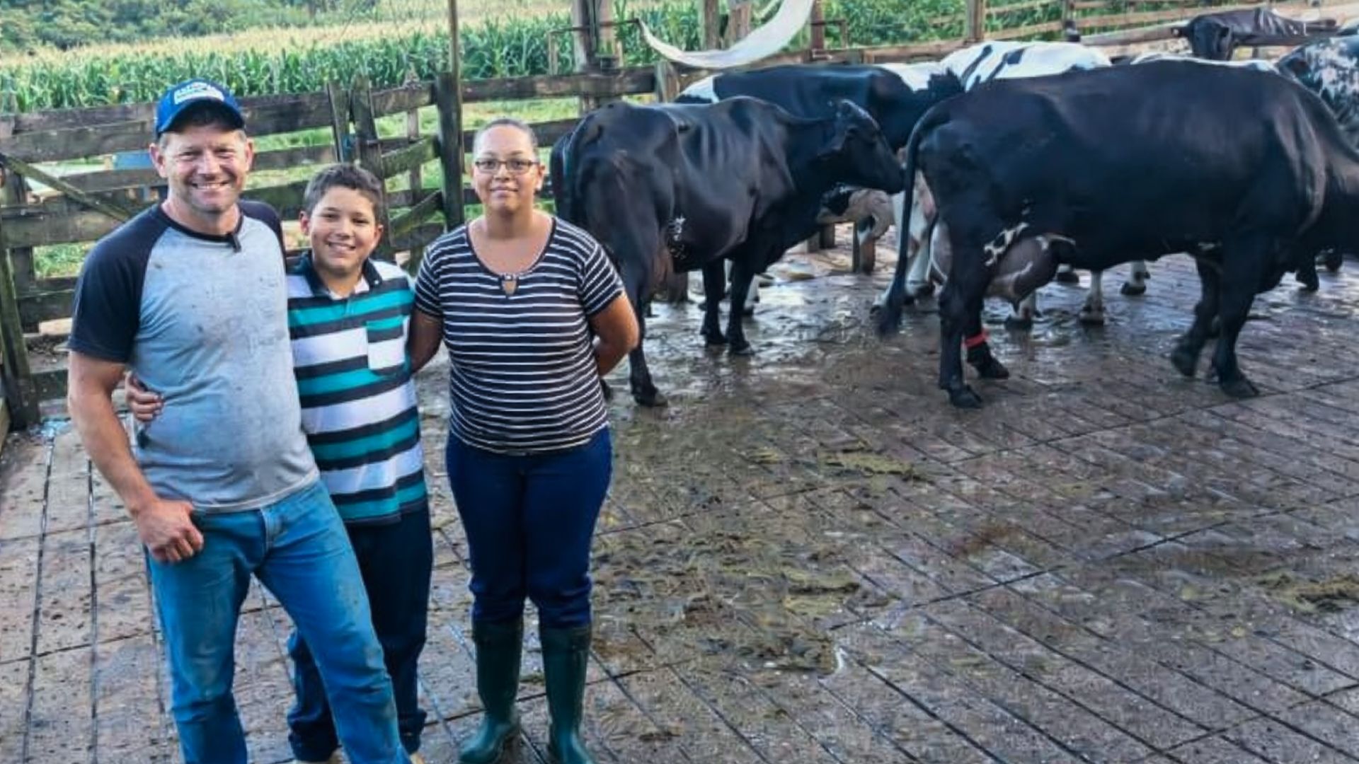 Família de produtores de leite em fazenda com barracão moderno e vacas leiteiras.
