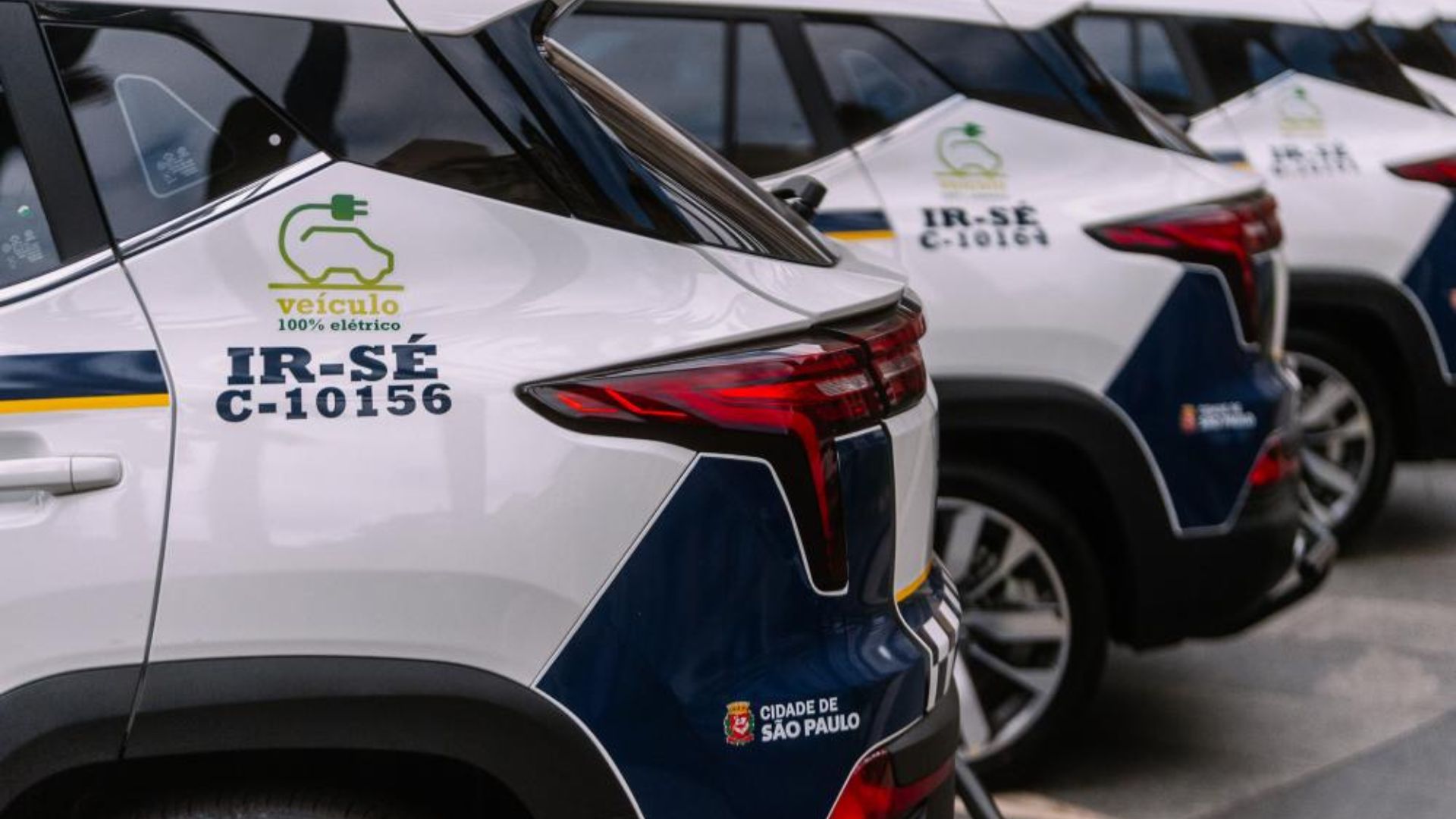 Viaturas elétricas da Guarda Civil Metropolitana de São Paulo estacionadas em fila, com identificação de veículo 100% elétrico e brasão da cidade.