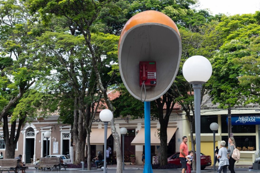En Itu, el teléfono gigante de 7 metros en la plaza de la Matriz permanece como memoria urbana tras la ANATEL desactivar teléfonos públicos. Entienda por qué se convirtió en identidad turística a 98 km de São Paulo.
