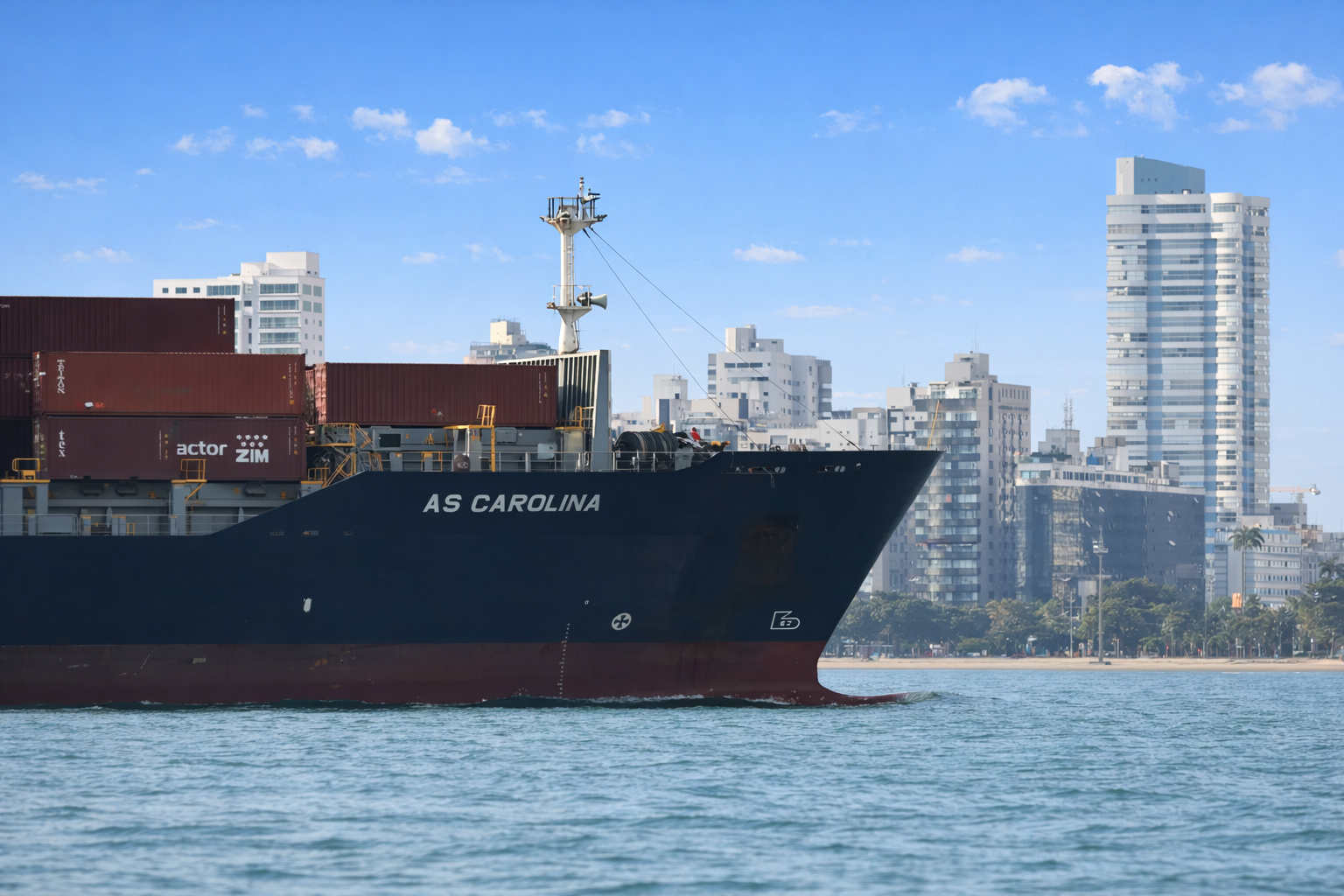 Navio cargueiro AS Carolina transportando contêineres próximo à orla urbana, sob céu azul com poucas nuvens.