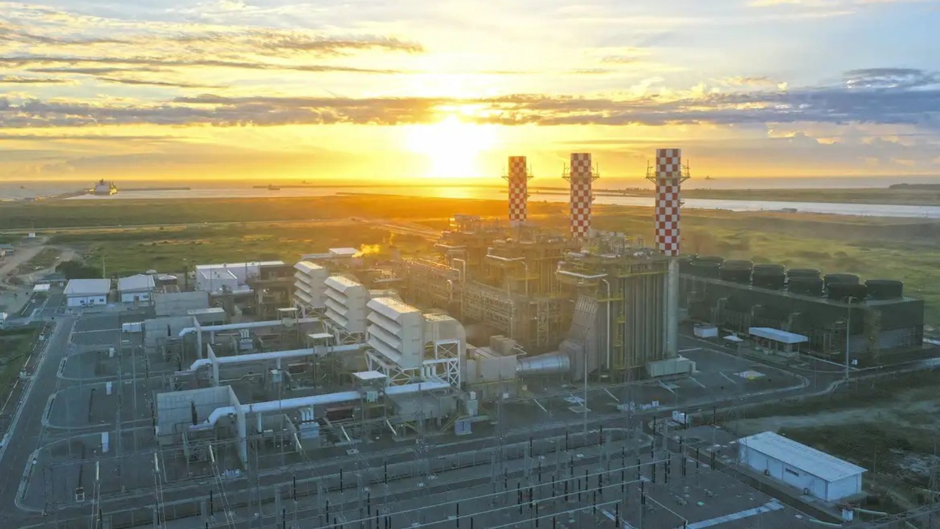 Usina termelétrica a gás natural no Porto do Açu ao pôr do sol, com chaminés industriais e infraestrutura energética de grande porte