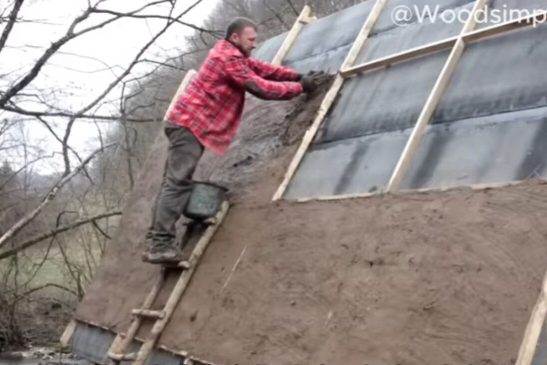Casa de madera con telhado de terra tiene aislamiento natural; patio de piedra y muebles hechos a mano completan el hogar.