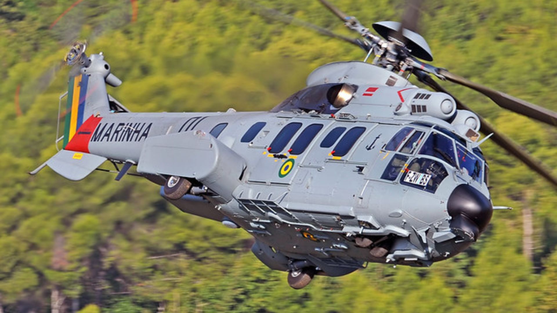 Helicóptero militar brasileiro usa carga externa para transportar outra aeronave, atuando como guindaste voador em missões logísticas reais.