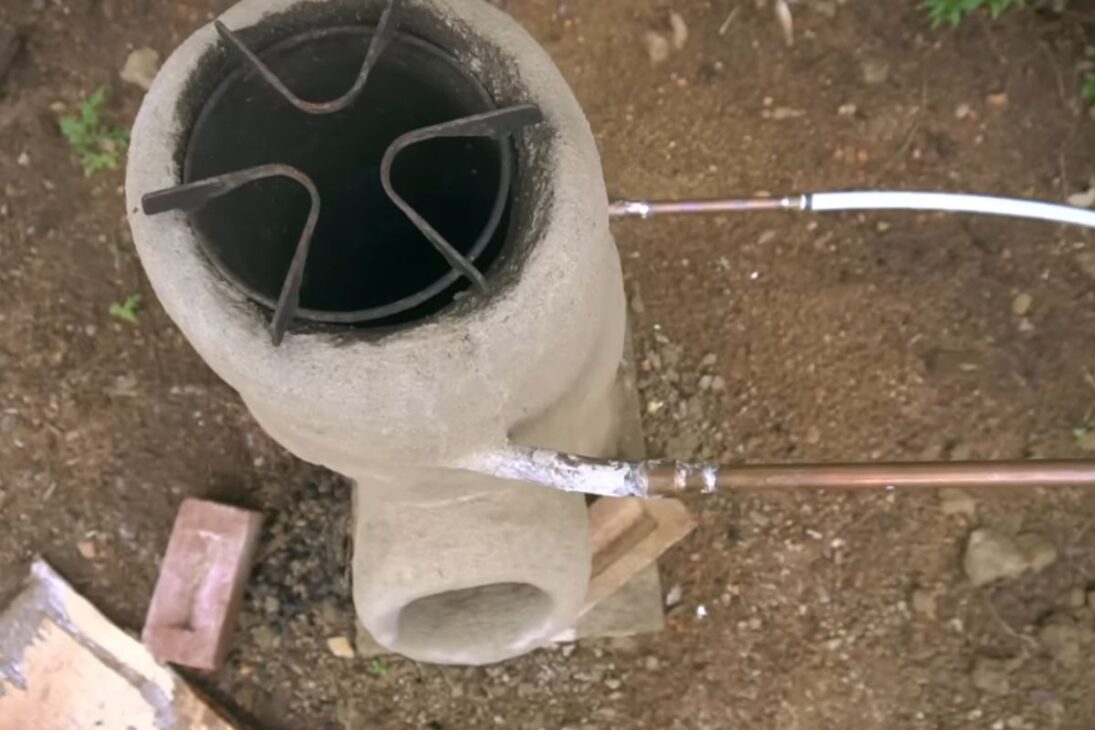 Calentador de agua fuera de la red en Quebec utiliza estufa cohete, barril elevado, tubos de cobre y termostato para calentar baño sin propano, bomba o electricidad, priorizando autonomía, eficiencia y atención a la seguridad en el uso diario.