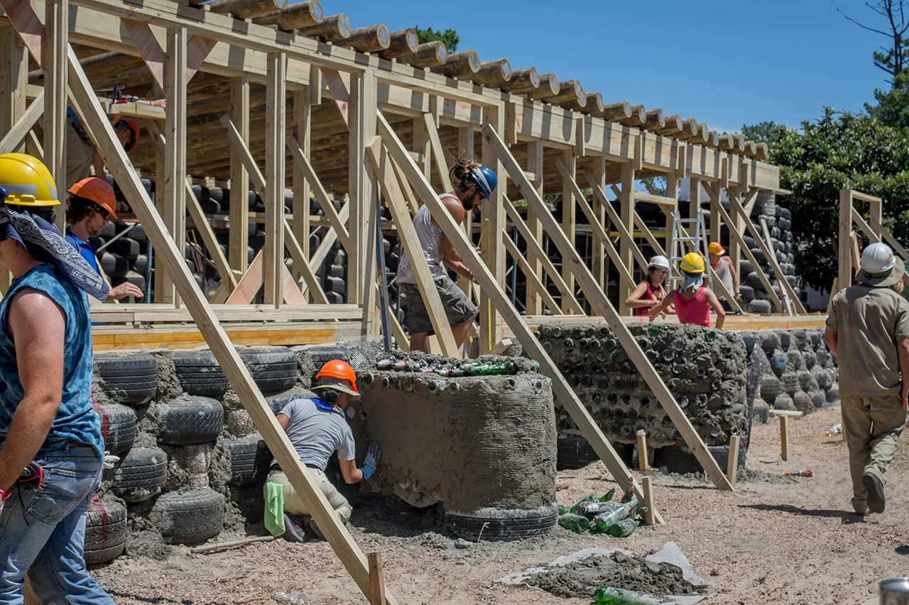 Sem arquiteto contratado, sem financiamento e usando pneus velhos, garrafas e terra, voluntários de 30 países construíram a primeira escola pública sustentável da América Latina em sete semanas e entregaram uma obra que não paga conta de luz, não paga conta de água e ainda produz alimento dentro das salas de aula