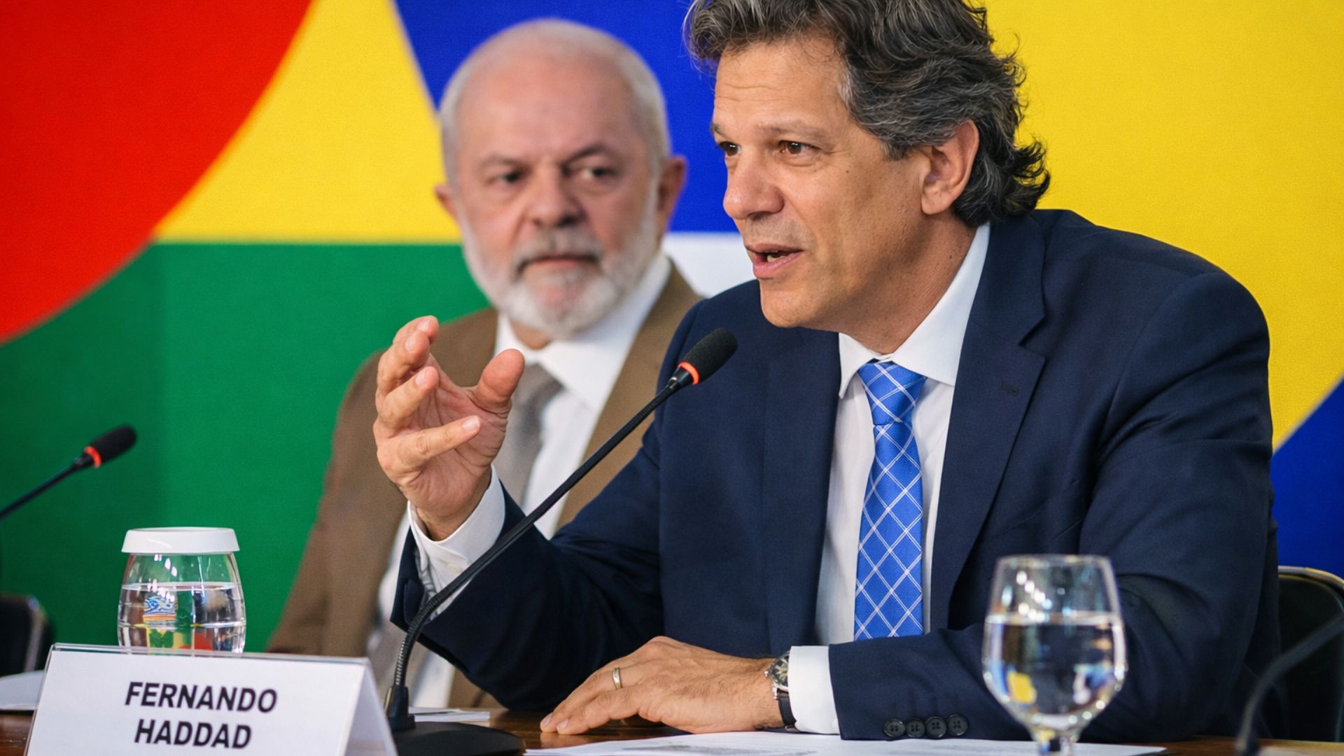 Fernando Haddad fala em conferência sobre economia e energia, com Lula ao fundo, em evento institucional do governo brasileiro.
