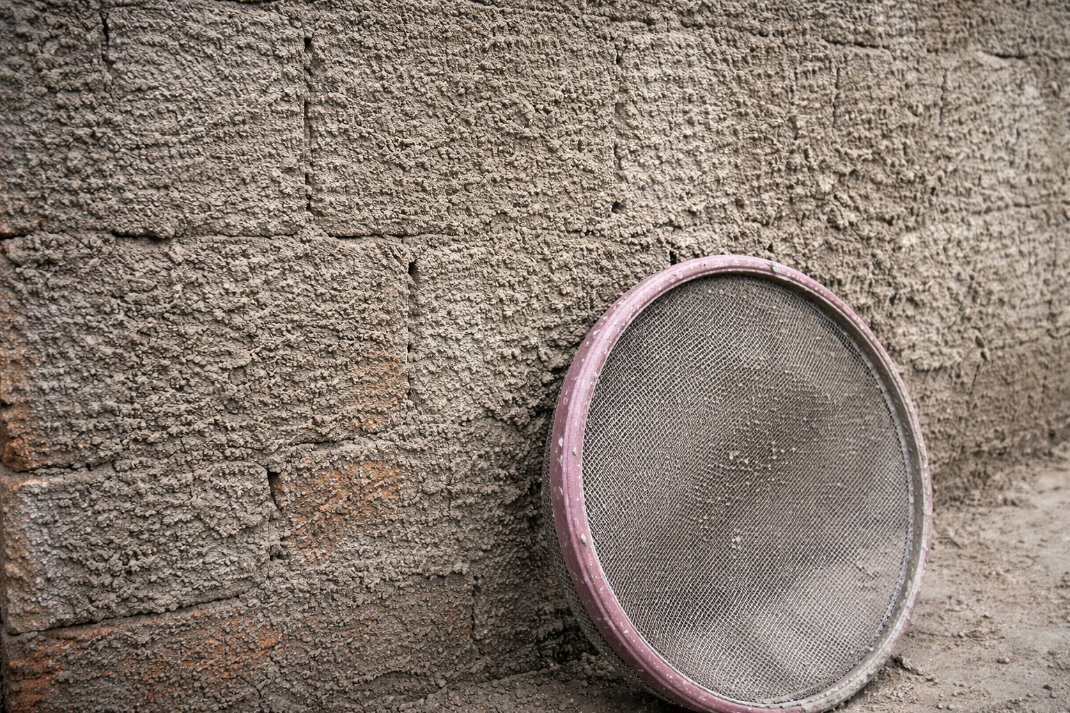 Pedreiro mostra como misturar argamassa e jogar na parede com peneira metálica simples na “Técnica de chapisco com peneira”, criando textura rústica tipo pedra que protege a fachada contra sol e chuva