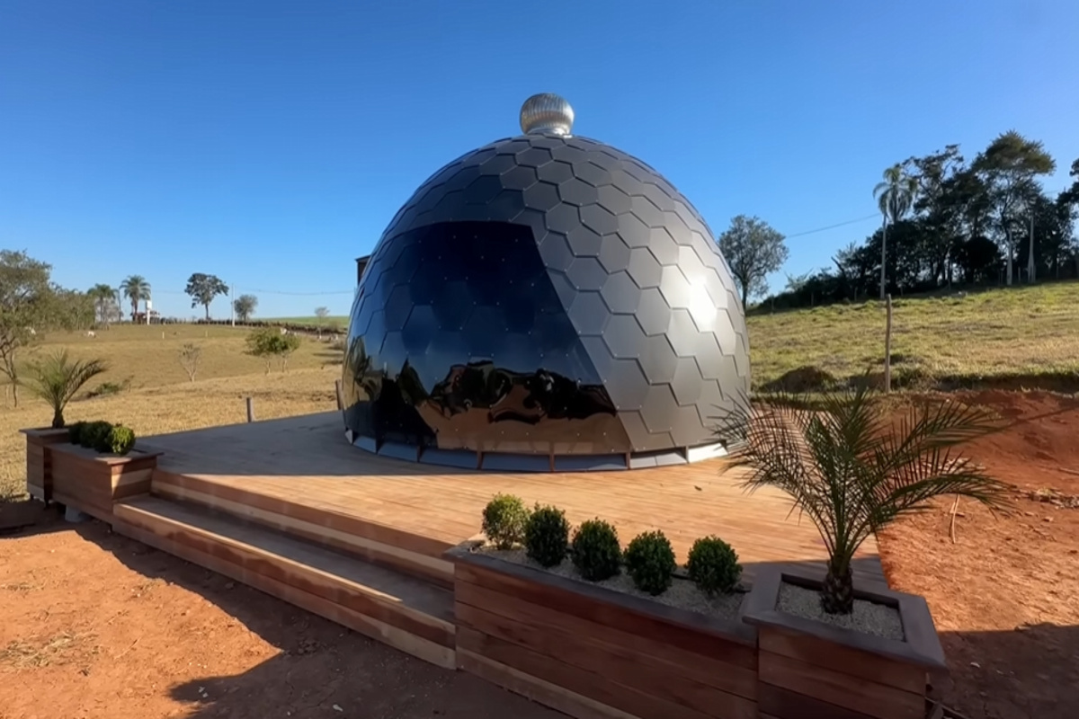 Domo geodésico revestido com placas hexagonais de ACM instalado sobre deck de madeira em área rural