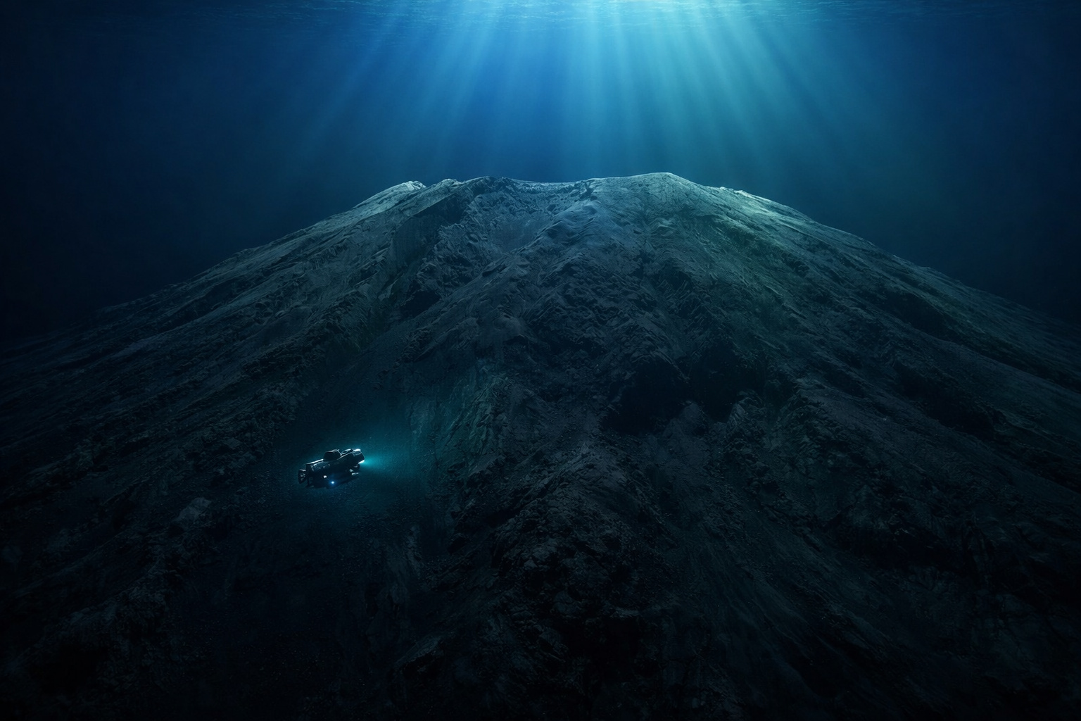 Submarino científico explorando o Maciço Tamu, gigantesca montanha vulcânica submersa no fundo do Oceano Pacífico iluminada por raios de luz vindos da superfície.