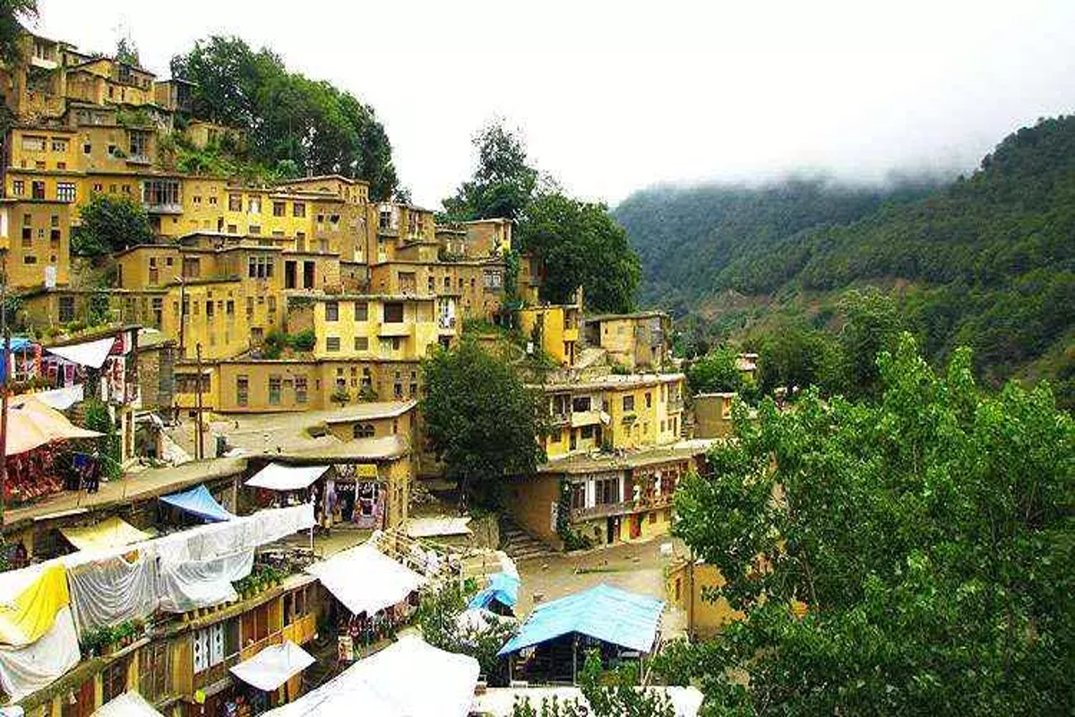 Vila histórica de Masouleh no Irã com casas amarelas em camadas na encosta da montanha, onde os telhados funcionam como ruas e pátios.